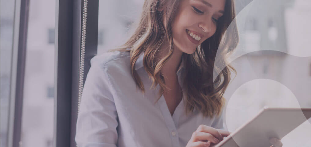 a girl smiling, reading something on a tablet