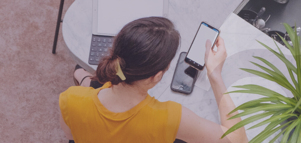 woman working on laptop and two phones