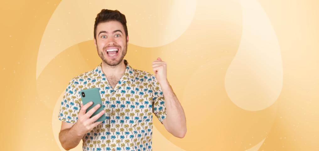 an excited man smiling and holding a phone