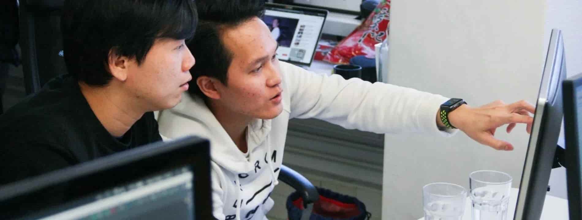 employee showing something to his coworker on monitor