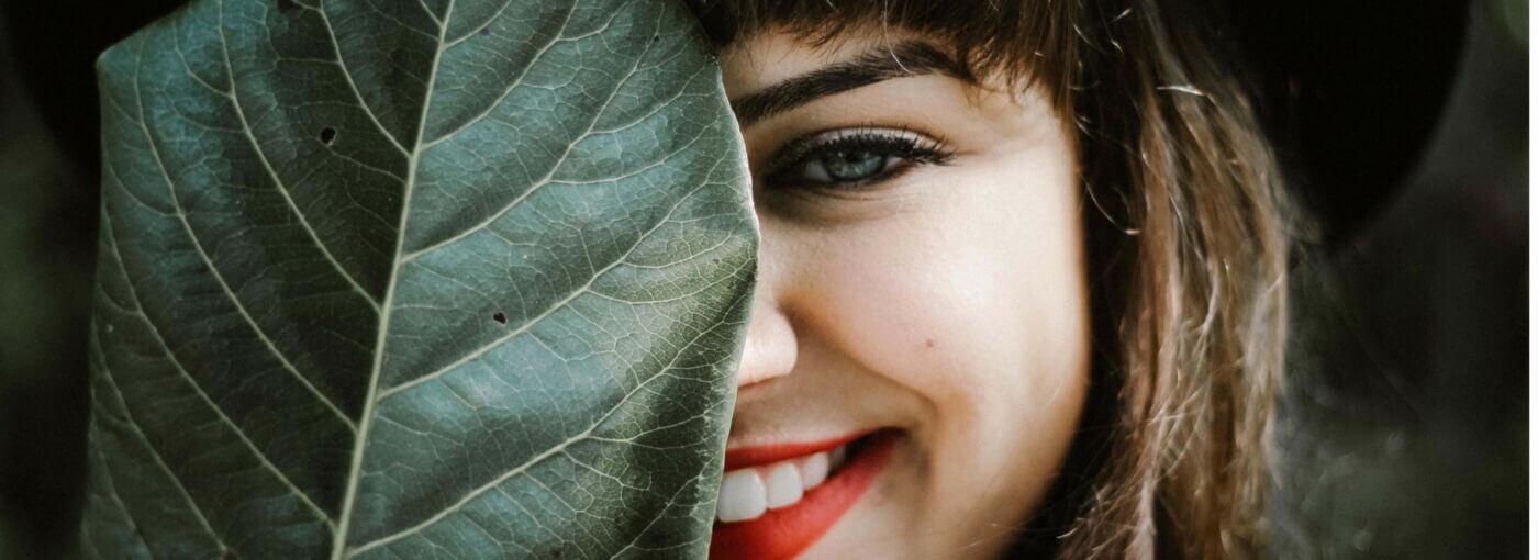 woman hiding her face behind a leaf