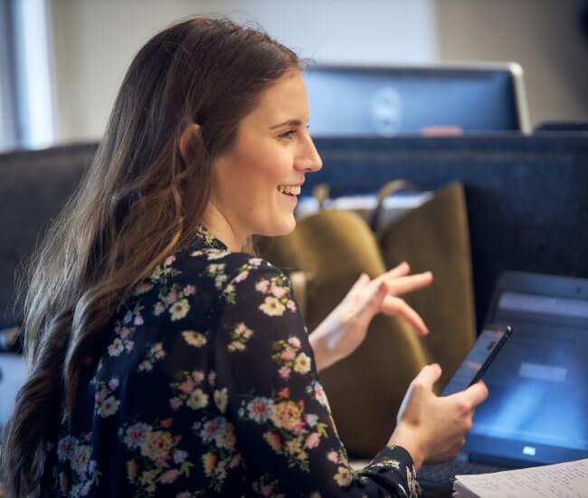 a woman smiling to someone while typing on phone